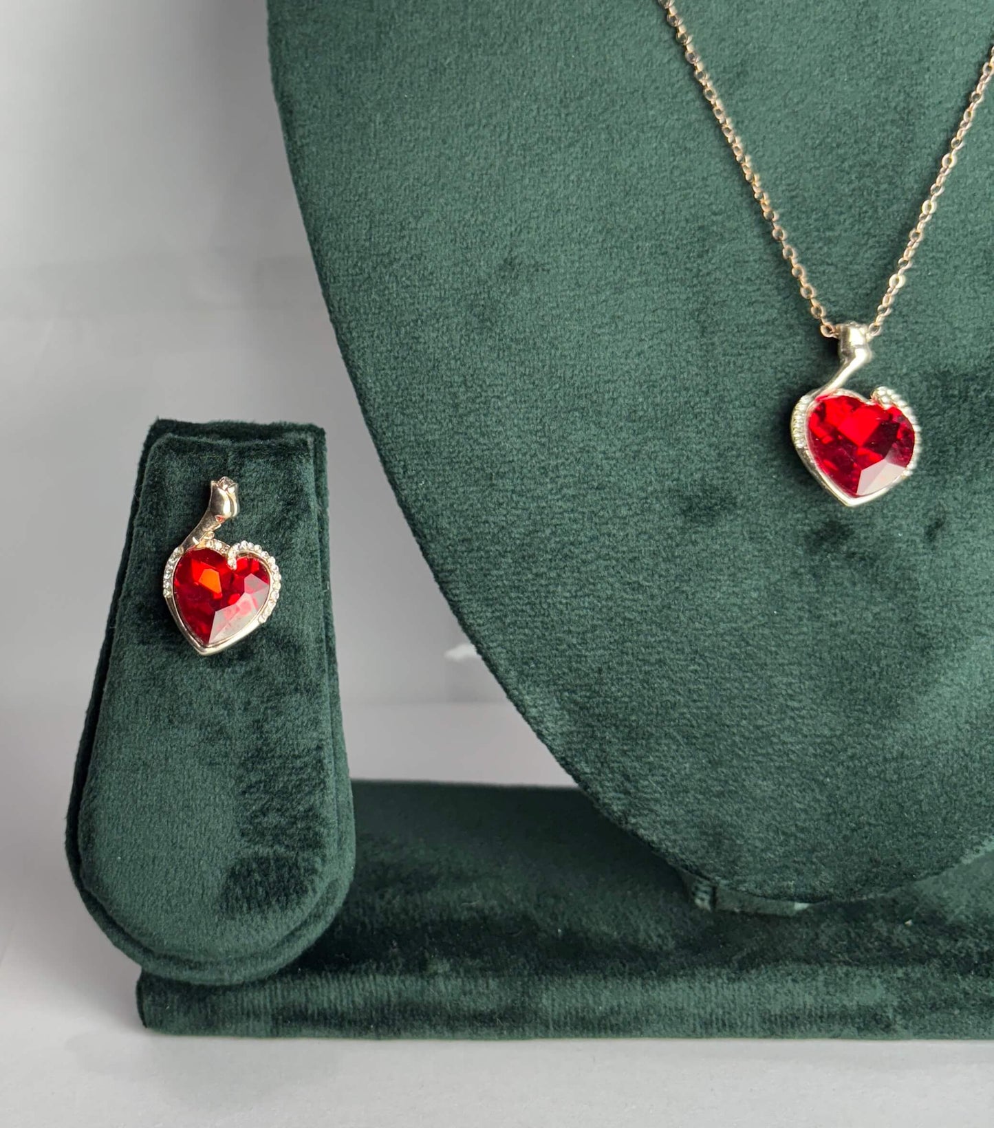 Heart-shaped red gemstone pendant on a gold chain displayed