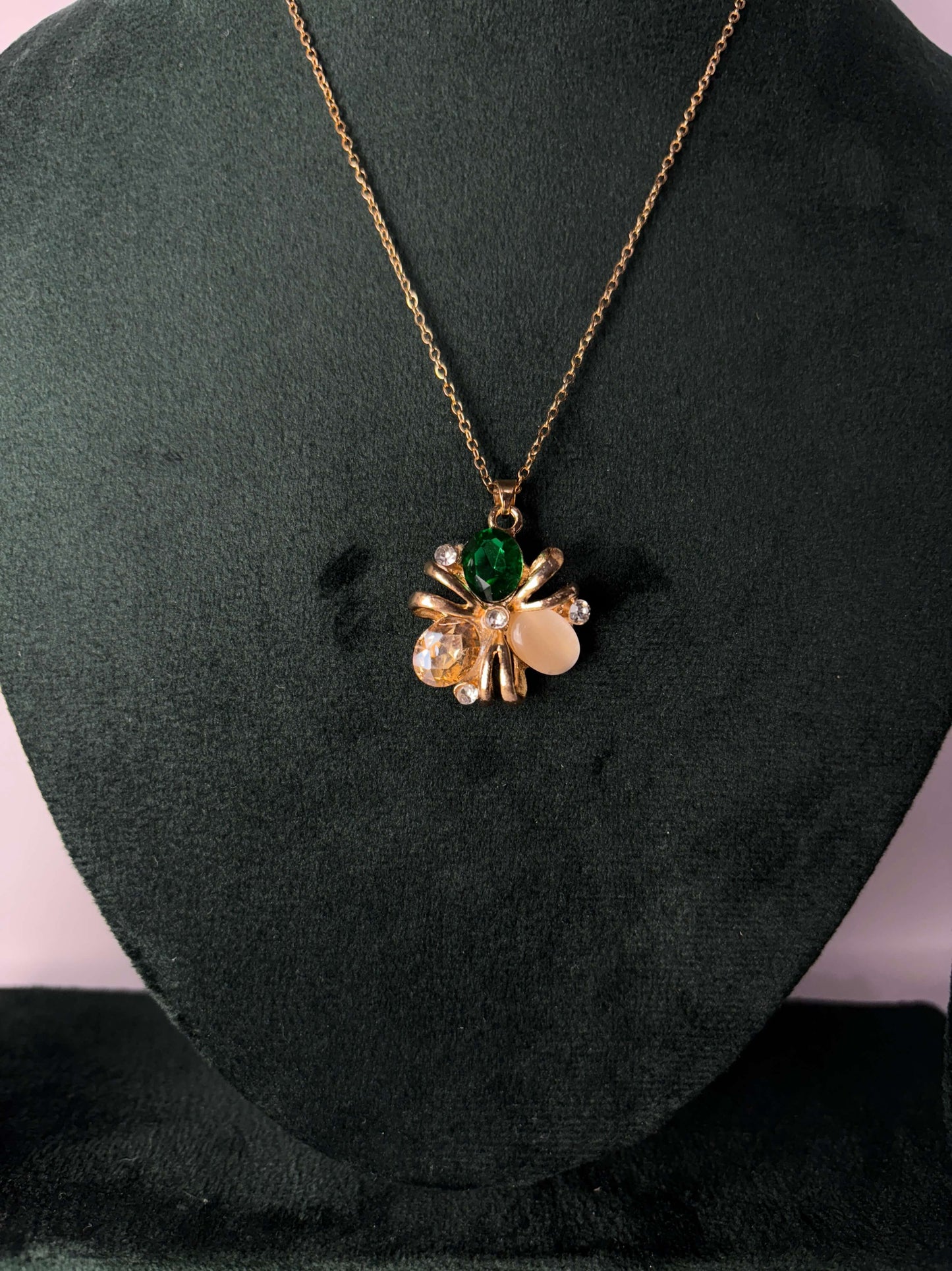 Gold necklace with a pendant featuring green and clear gemstones