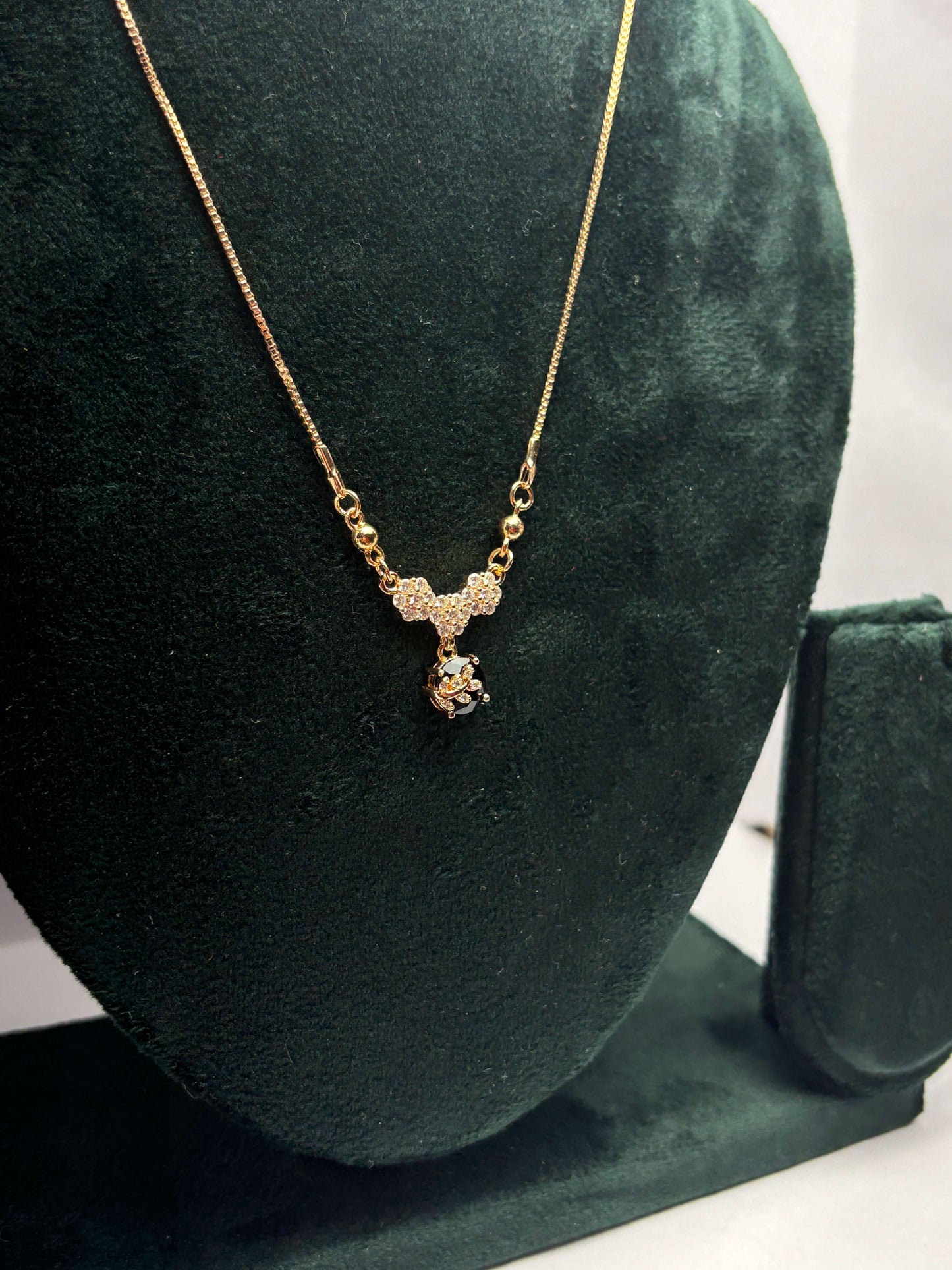Gold necklace with a pendant on a green velvet stand