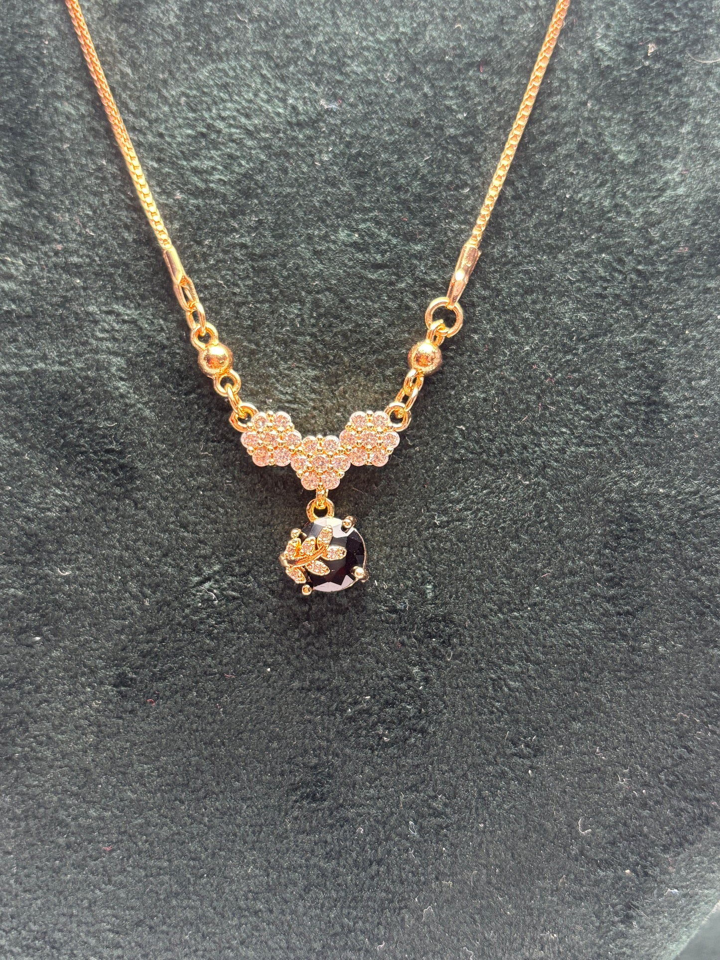 Gold necklace with a black bead on a dark gray surface