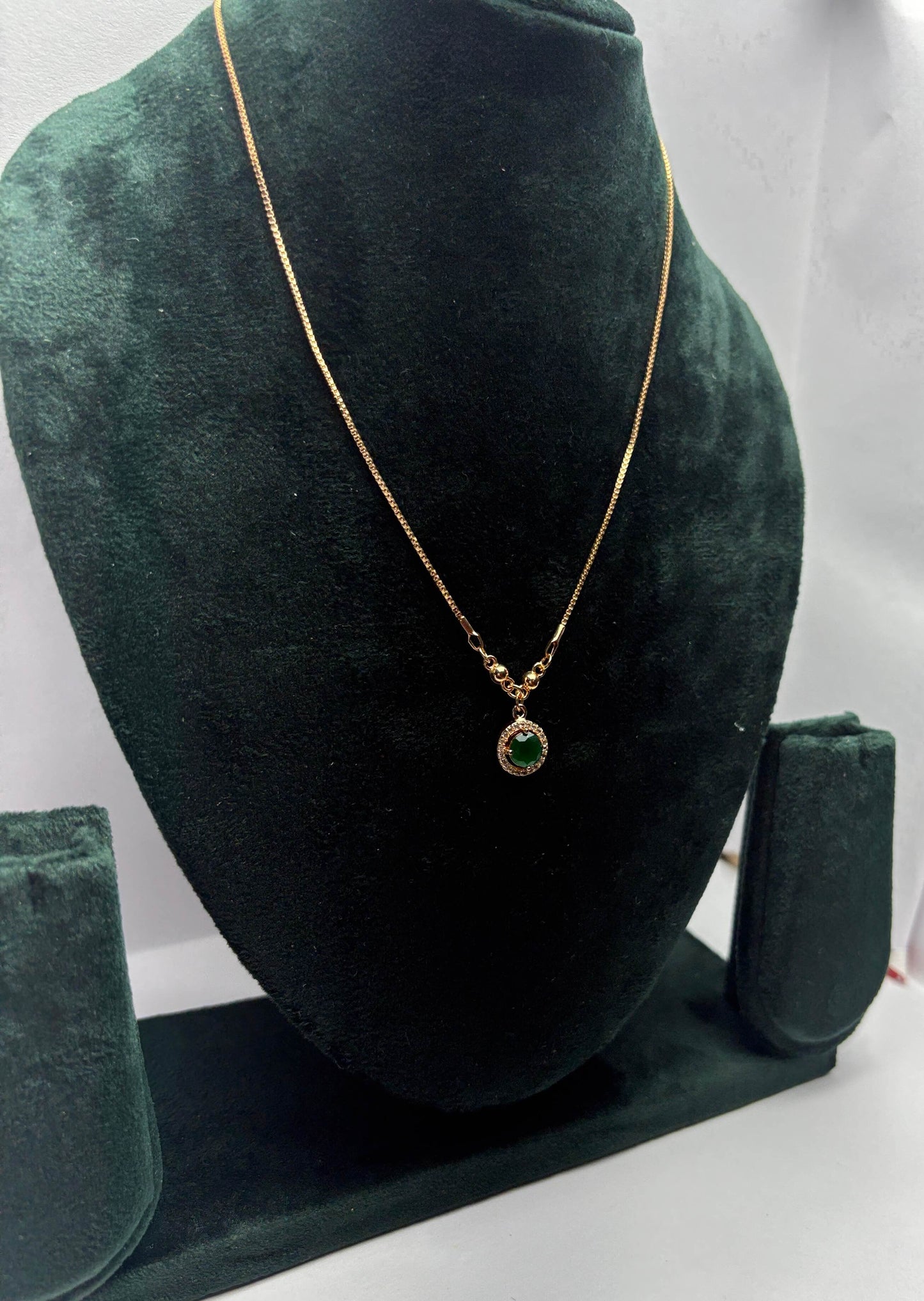 Gold necklace with a green gemstone pendant.