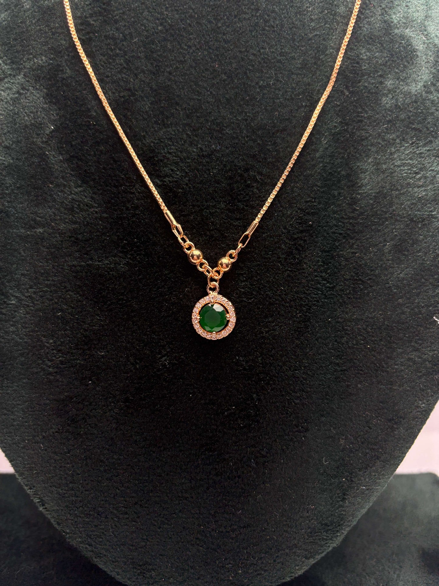 Gold necklace with a green gemstone pendant.