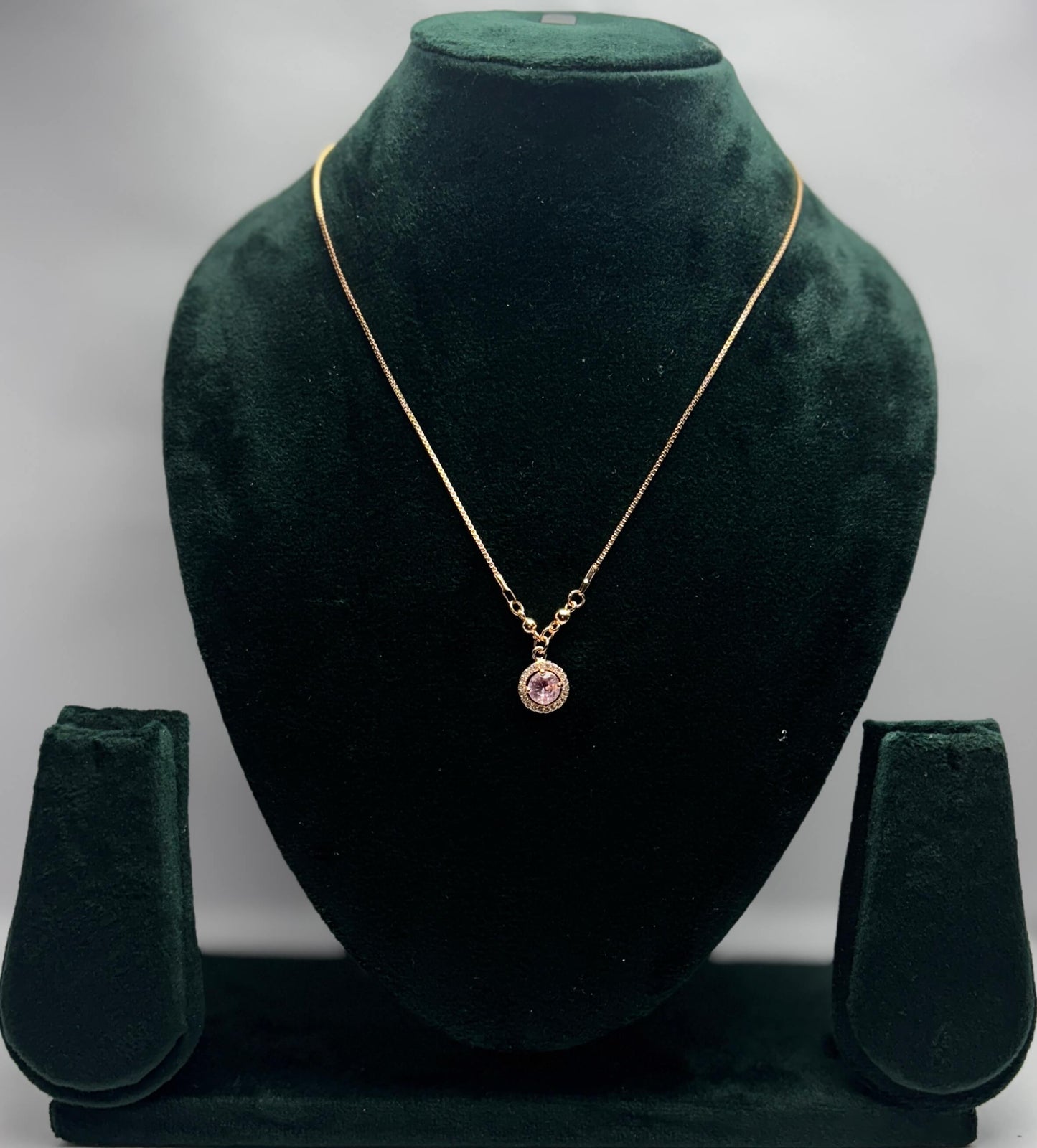 Gold necklace with a pink pendant.
