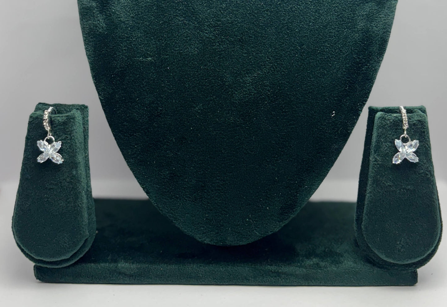 Pair of butterfly-shaped earrings on a green velvet stand.