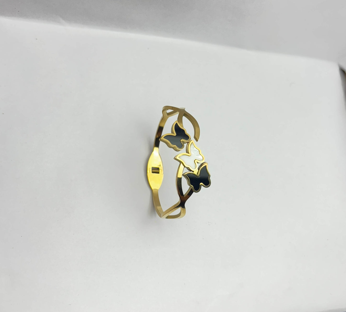 Gold ring with black butterfly design on a light gray background