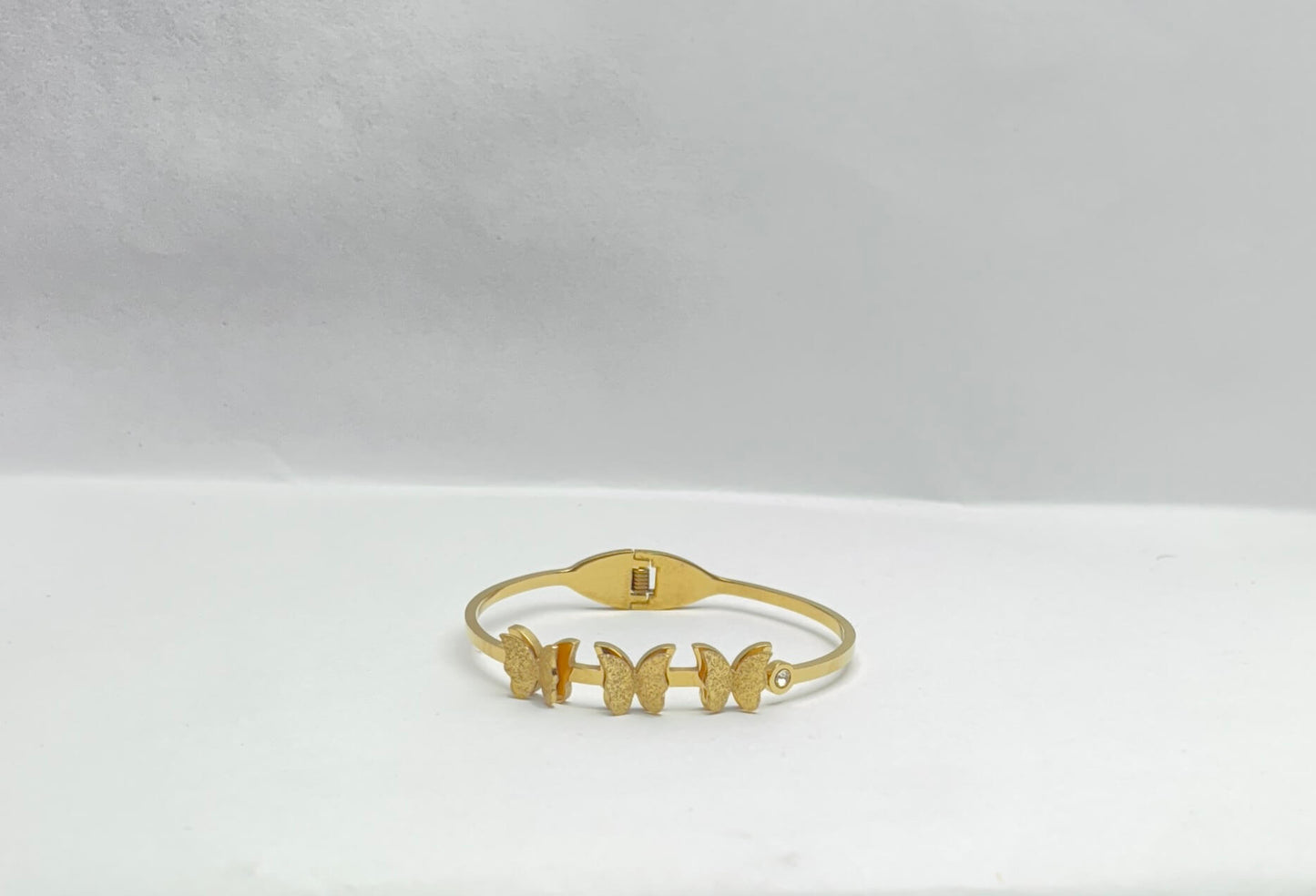 Gold bracelet with butterfly designs on a white background