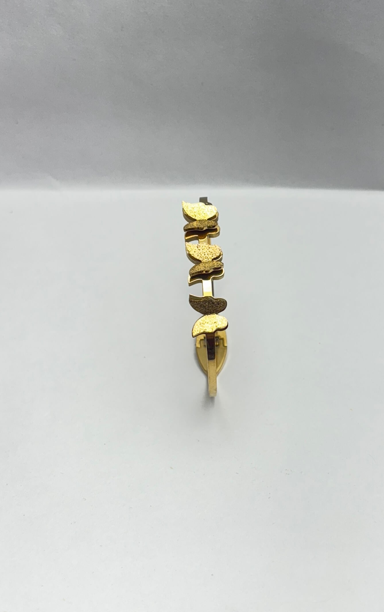 Gold butterfly bracelet on a light gray background