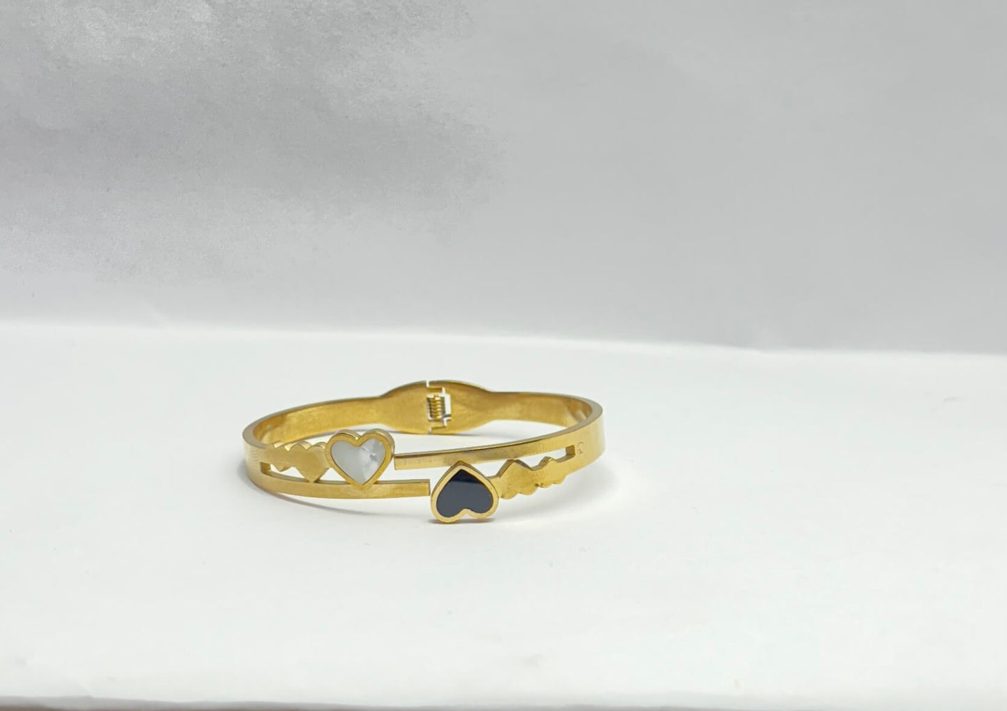 Gold bracelet with heart-shaped charms on a light gray background