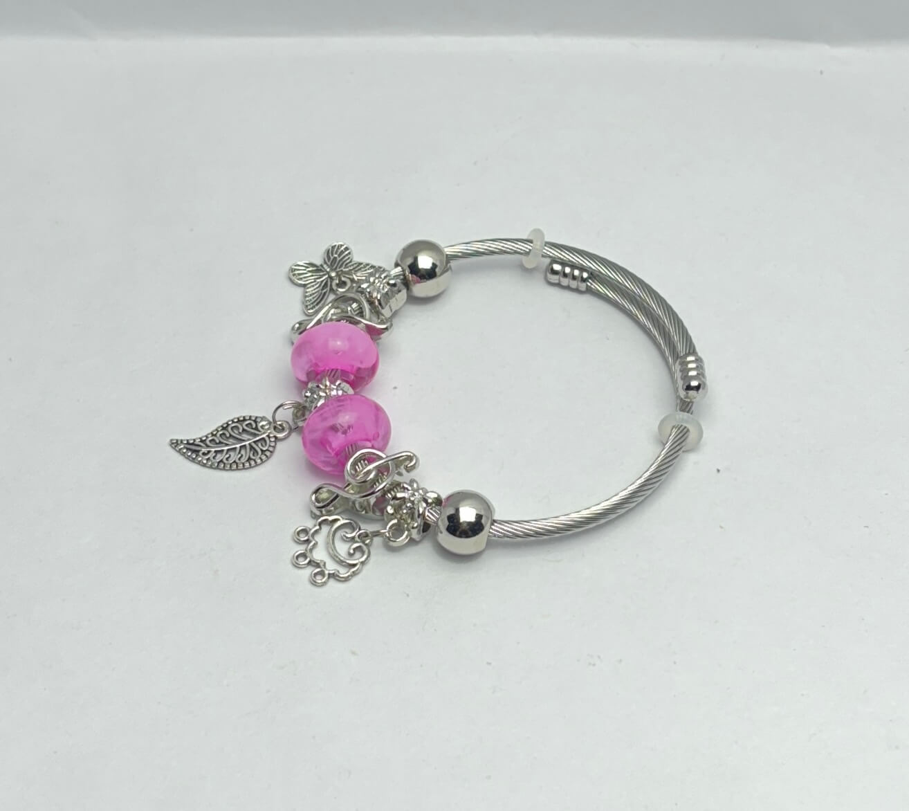 Silver bracelet with pink beads and charms on a white background