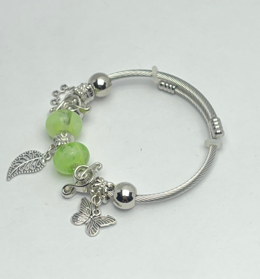 Silver bracelet with green beads and charms on a white background