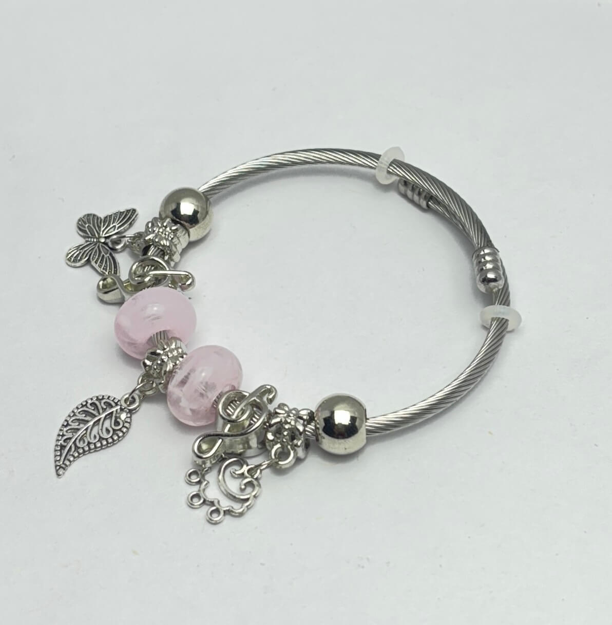 Silver bracelet with pink beads and charms on a white background