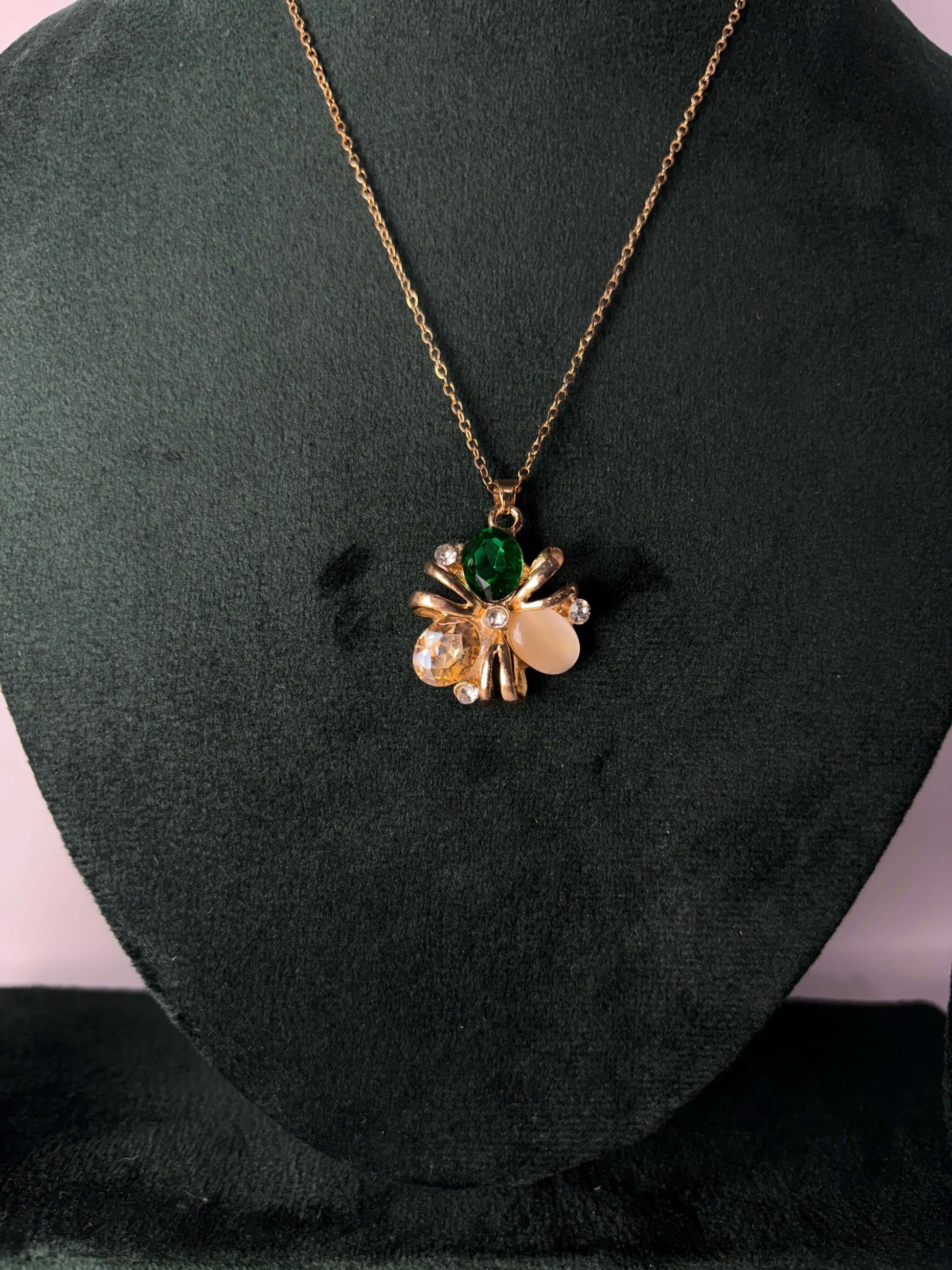 Gold necklace with a pendant featuring green and clear gemstones 