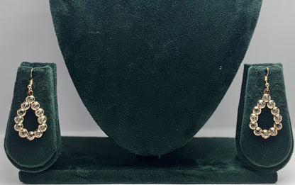 Pair of gold earrings on a green velvet stand