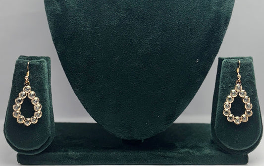 Pair of gold earrings on a green velvet stand