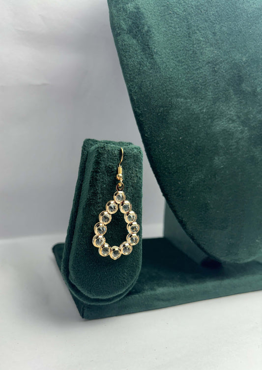 Teardrop-shaped earrings on a green velvet stand with a green cushion in the background