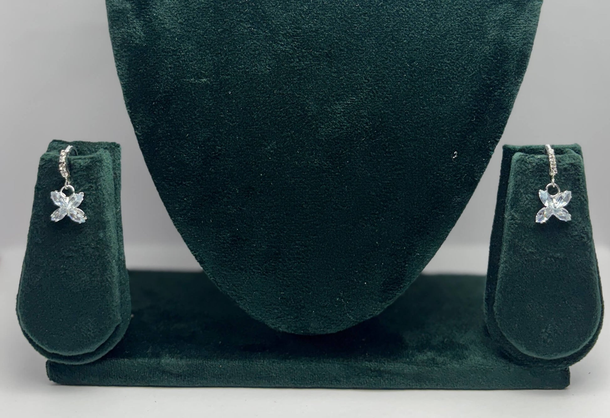 Pair of butterfly-shaped earrings on a green velvet stand.