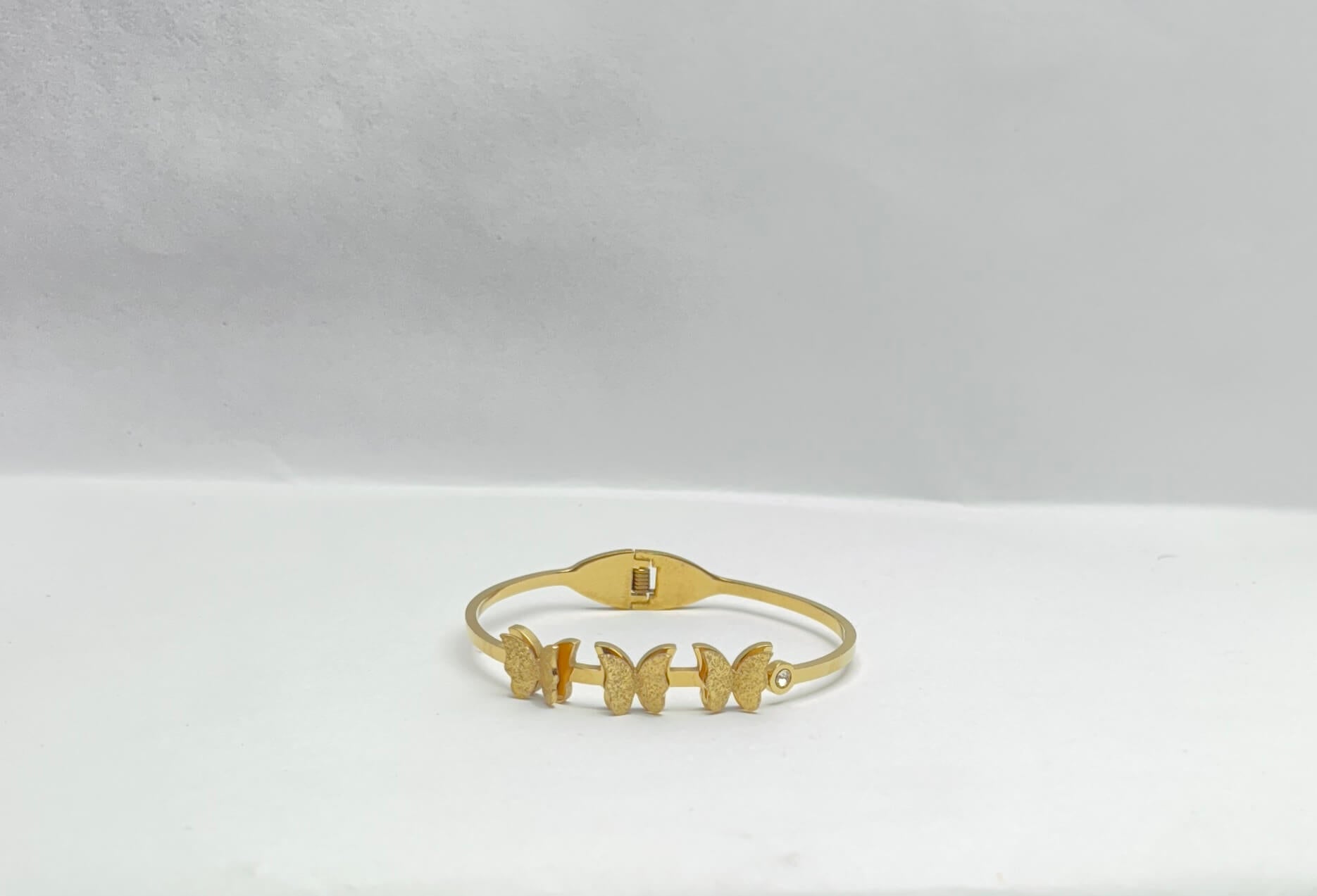Gold bracelet with butterfly designs on a white background