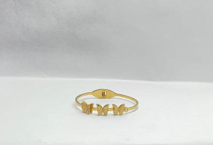 Gold bracelet with butterfly designs on a white background