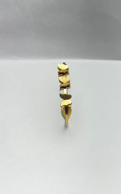 Gold butterfly bracelet on a light gray background