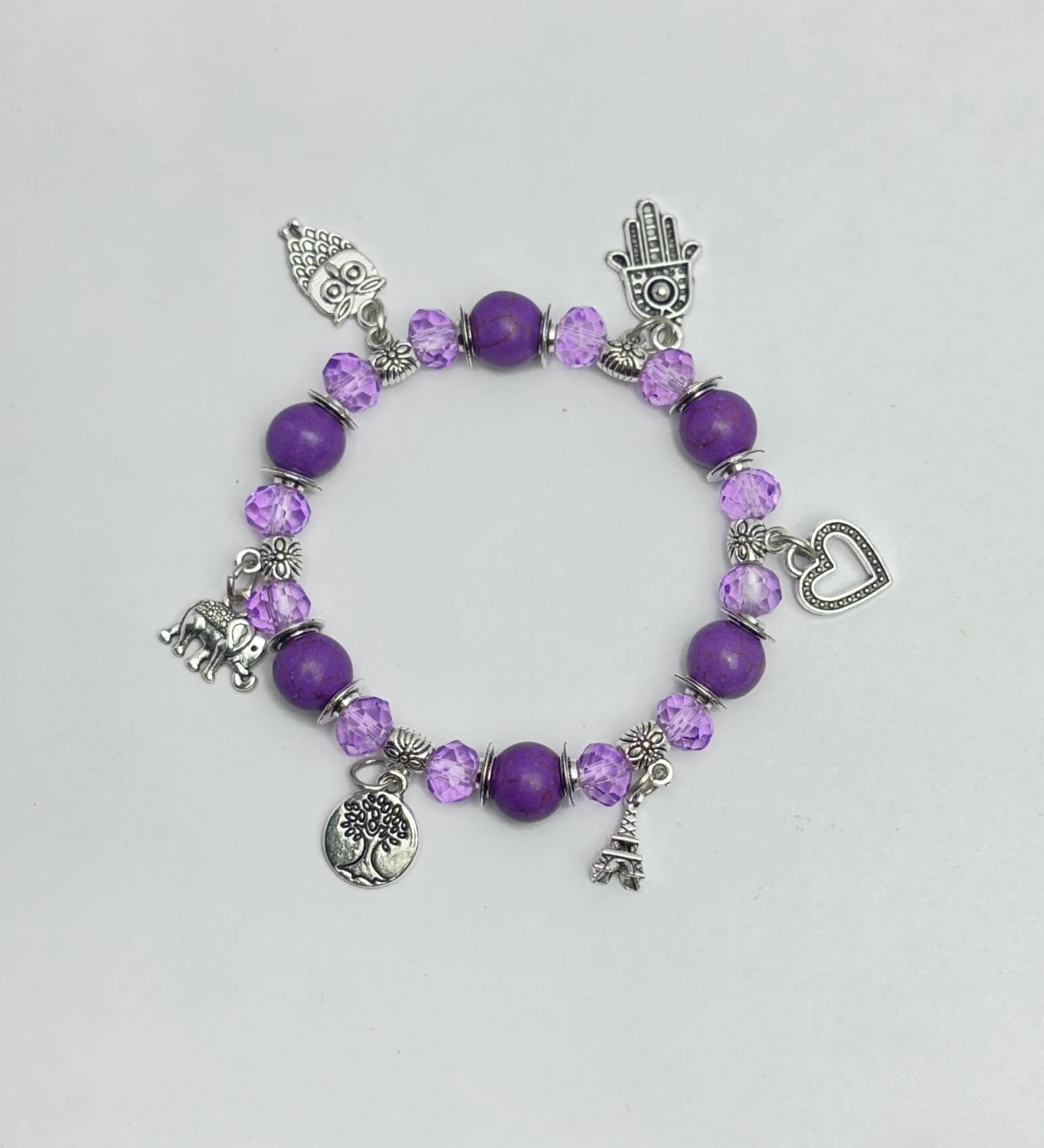 Purple beaded bracelet with various charms on a light gray background