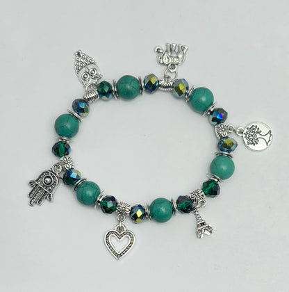 Bracelet with green beads and various charms on a light gray background