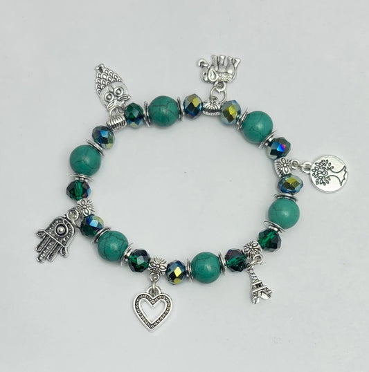 Bracelet with green beads and various charms on a light gray background
