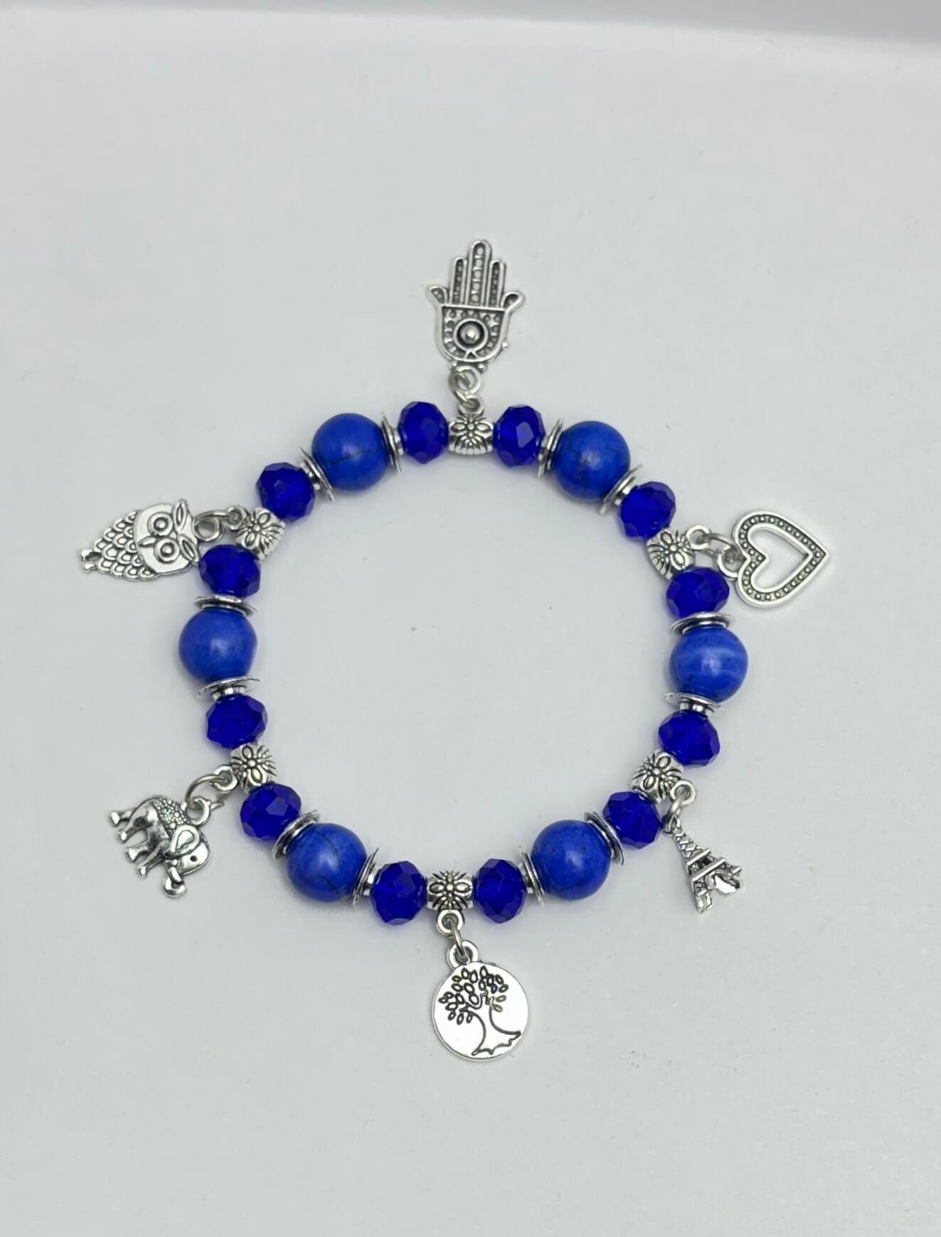 Blue beaded bracelet with various silver charms on a white background