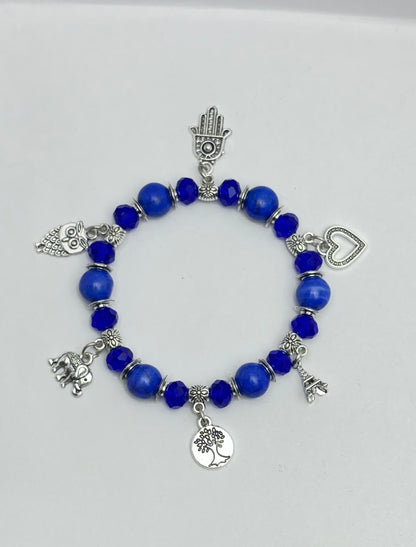 Blue beaded bracelet with various silver charms on a white background
