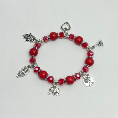 Bracelet with red beads and various silver charms on a light gray background