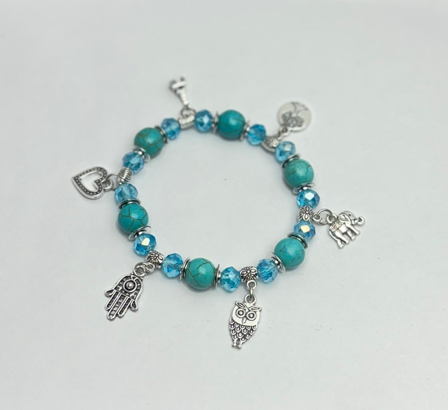 Turquoise beaded bracelet with charms on a light gray background