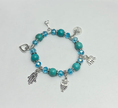 Turquoise beaded bracelet with charms on a light gray background