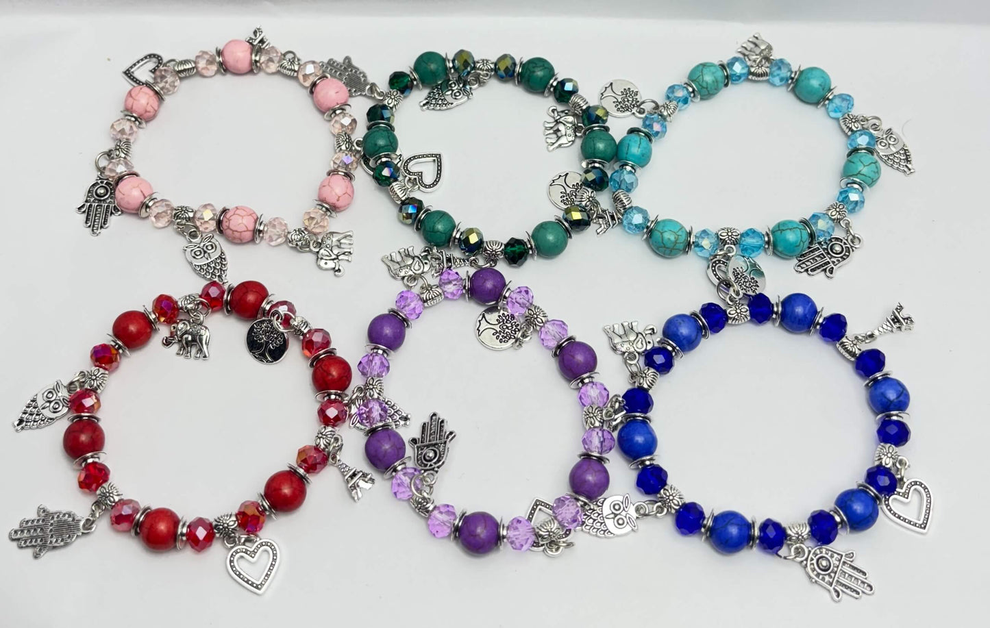 Set of colorful beaded bracelets with charms on a white background