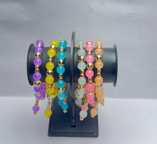 Colorful beaded bracelets on a black stand against a white background
