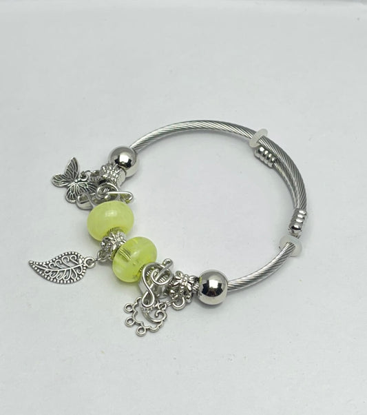 Silver bracelet with green beads and charms on a white background